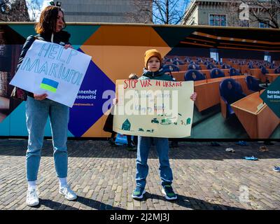 La Haye, pays-Bas. 02nd avril 2022. Une mère ukrainienne et son fils ont vu tenir des placards contre la guerre pendant la manifestation. Une installation artistique ukrainienne a été placée devant la Chambre des représentants des pays-Bas, pour attirer l'attention des autorités néerlandaises et de la population sur les meurtres de civils et en particulier d'enfants pendant la guerre en Ukraine. Crédit : SOPA Images Limited/Alamy Live News Banque D'Images