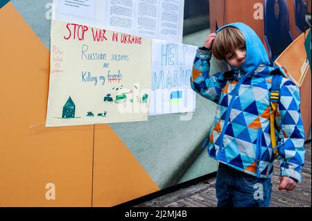 La Haye, pays-Bas. 02nd avril 2022. Un garçon ukrainien a vu se tenir près d'un écriteau contre la guerre pendant la manifestation. Une installation artistique ukrainienne a été placée devant la Chambre des représentants des pays-Bas, pour attirer l'attention des autorités néerlandaises et de la population sur les meurtres de civils et en particulier d'enfants pendant la guerre en Ukraine. Crédit : SOPA Images Limited/Alamy Live News Banque D'Images