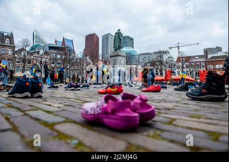 La Haye, pays-Bas. 02nd avril 2022. Chaussures disposées en rangées sur la plaine de Het, pendant que des adultes et des enfants ont drapé dans les drapeaux ukrainiens pendant la manifestation. Une installation artistique ukrainienne a été placée devant la Chambre des représentants des pays-Bas, pour attirer l'attention des autorités néerlandaises et de la population sur les meurtres de civils et en particulier d'enfants pendant la guerre en Ukraine. Crédit : SOPA Images Limited/Alamy Live News Banque D'Images