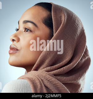 Elle était belle, pour la façon dont elle a pensé. Photo studio d'une belle jeune femme portant un foulard sur fond gris. Banque D'Images