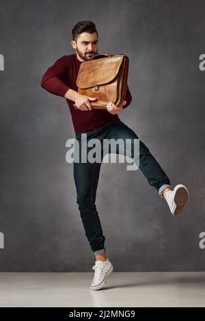 Il a fait un bruit de frappe. Studio photo d'un beau jeune homme posant avec un sac sur un fond sombre. Banque D'Images