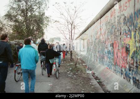 Berlin Ouest, Allemagne, 10 jours après la détente du passage frontalier par le gouvernement de la RDA. Cela a permis aux citoyens de l'Allemagne de l'est de traverser Berlin Ouest et Allemagne de l'Ouest, photos prises le 19th novembre 1989. Photo : les gens marchent à côté des graffitis couverts mur de Berlin Banque D'Images