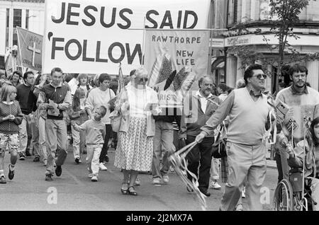 Clowns, poussettes et choeurs se sont tous avéré pour stimuler la deuxième marche annuelle pour Jésus. Des centaines de churchgoers locaux ont assisté à la marche, l'un des nombreux qui se tiennent dans tout le pays pour diffuser le message du christianisme. Le thème de la marche interconfessionnelle de cette année était le rôle de la religion dans l'éducation des enfants. Les marcheurs ont suivi un itinéraire depuis Greenhead Park, à travers le centre-ville, chantant des hymnes et distribuant des tracts. À la suite de la marche, le prédicateur Daniel Cozens parlera plus tard dans le mois à l'église méthodiste Holmfirth et à l'église Elim. 15th septembre 1990. Banque D'Images