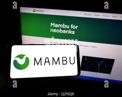 Personne tenant un smartphone avec le logo de la société fintech allemande Mambu GmbH à l'écran devant le site Web. Mise au point sur l'affichage du téléphone. Banque D'Images