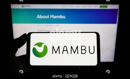 Personne tenant un téléphone portable avec le logo de la société fintech allemande Mambu GmbH sur l'écran en face de la page Web d'affaires. Mise au point sur l'affichage du téléphone. Banque D'Images