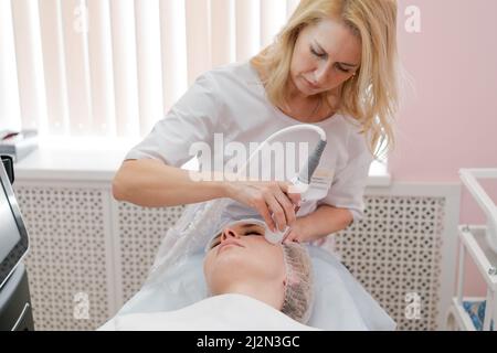 Appareil de massage de drainage lymphatique processus de massage. Un thérapeute cosmetologiste propose un massage du visage rajeunissant pour une femme dans un salon de spa. Concept beauté et corps. Banque D'Images