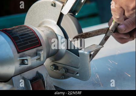 Affûtage manuel des ciseaux à l'aide d'outils à main. Mains circoncis d'une personne inconnue aiguiser des ciseaux sur Une machine à écrire. L'homme aiguise des ciseaux Banque D'Images