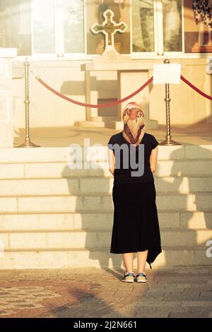 Ostrog Monastère, femme pèlerine avec voile prie devant une croix orthodoxe - le Monténégro Banque D'Images