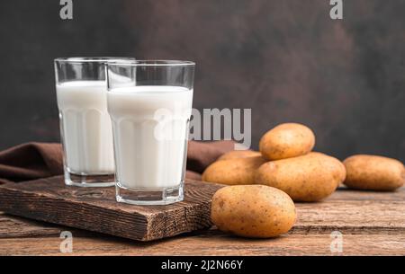 Lait de pomme de terre dans deux verres sur fond marron. Lait végétarien. Banque D'Images