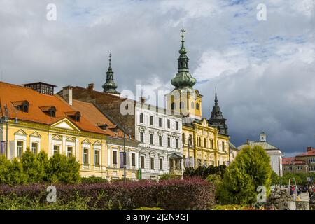 Banska Bystrica, Slovaquie - 17 août 2021 : vue sur la place SNP - bâtiments historiques colorés, château de Mestsky Grad, arbres verts et personnes marchant aro Banque D'Images