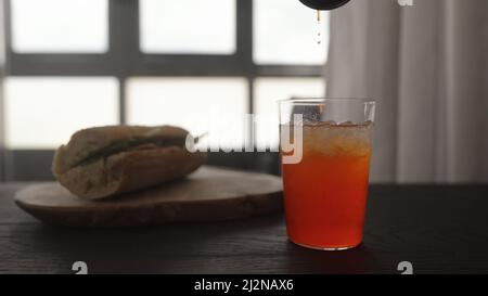 verser le sirop d'orange dans la limonade dans le verre à verre droit, photo large Banque D'Images