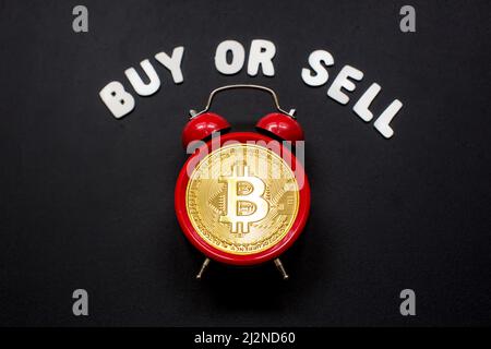 Bitcoin et réveil avec panneau « Acheter ou vendre ». Concept de date limite pour investir dans la crypto-monnaie en bitcoin. Banque D'Images
