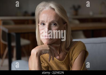 Blonde souriante d'âge moyen 60s dame à la maison tête tourné portrait Banque D'Images
