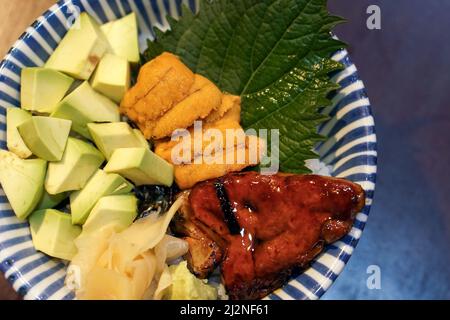 Bol à riz mélangé pour aliments frais de qualité supérieure. Riz japonais avec Uni, foie gras et avocat décoré de feuilles de shiso vertes. Vue de dessus Banque D'Images