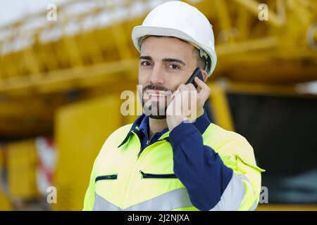 un travailleur en casque blanc parle sur un téléphone portable Banque D'Images