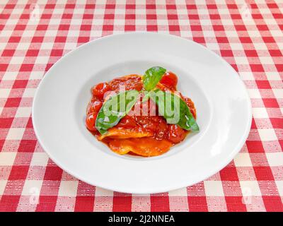 Assiette de pâtes aux raviolis avec sauce tomate fraîche et basilic sur nappe Banque D'Images