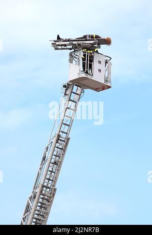 pompier qui sauve la personne blessée en utilisant le camion avec un long camion à échelle en cas d'urgence Banque D'Images