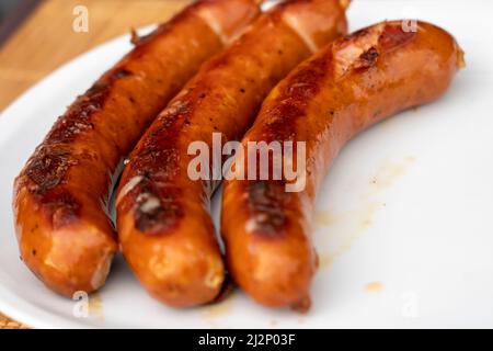 Barbecue à saucisses juteuses grillées Sizzle on avec sel et poivrons noirs sur White plate pour le déjeuner barbecue grillé pour pique-nique en été.Bratwurst ou hot dogs on Banque D'Images