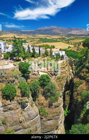 Vue sur l'ancien village Ronda situé precarily près du bord de la falaise abrupte, ciel bleu clair avec le nuage duveteux - Andalousie, Espagne Banque D'Images