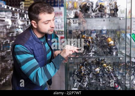 Jeune homme choisit bobine de baitcasting pour tige Banque D'Images