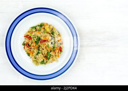 Couscous avec légumes et assaisonnements, préparés à partir d'un mélange congelé sur une table blanche Banque D'Images