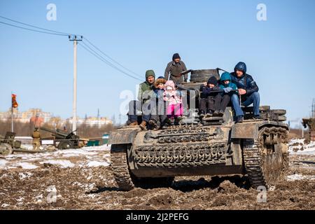 Saint-Pétersbourg, Russie - 27 mars 2022 : des enfants non identifiés avec leurs pères se mettent sur un char allemand de la deuxième guerre mondiale. Parc militaire acier Banque D'Images