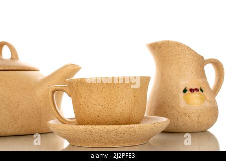 Une tasse en céramique avec soucoupe, théière, pot à lait, macro, isolée sur fond blanc. Banque D'Images