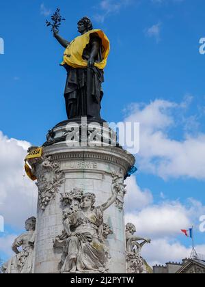 Monument à la République, orné d'un gilet jaune et bleu aux couleurs du drapeau ukrainien, avec le symbole de la rébellion d'extinction, mouvement international social environnemental, en signe de protestation de la guerre en Ukraine et de la surutilisation du pétrole et de son rôle dans la destruction du climat. 2 avril 2022, Paris, France Banque D'Images