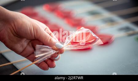 Lollipop rouge en forme de coeur dans les mains des femmes, gros plan. Banque D'Images