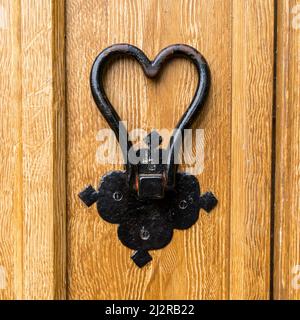 Porte en fer forgé en forme de coeur peint en noir sur porte en bois peint avec effet de faux-grain brun clair. Banque D'Images