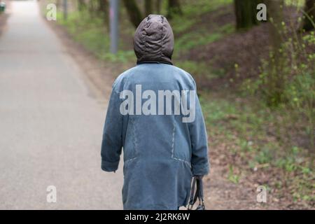 Une femme marche dans le parc. Une femme âgée seule dans la rue. Un homme marche. Tirer une femme de l'arrière. Banque D'Images