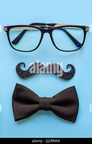 Gros plan des lunettes, de la moustache, du concept de cravate avec la fête des pères sur fond bleu, vertical. Banque D'Images