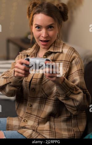 Une fille avec un joystick dans ses mains joue avec enthousiasme un jeu vidéo dans la salle. Gros plan. Jeux vidéo, nouvelles technologies, loisirs, e-spo Banque D'Images