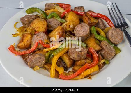 saucisses italiennes sucrées avec pommes de terre rôties rouges servies avec poivrons et oignons sautés, Banque D'Images