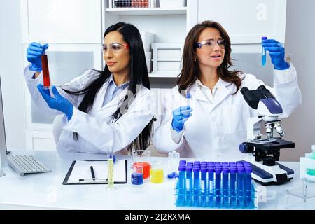 Deux belles jeunes femmes scientifiques travaillant en laboratoire avec des tubes à essai faisant de la recherche pharmaceutique Banque D'Images