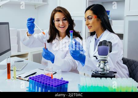 Deux belles jeunes femmes scientifiques travaillant en laboratoire avec des tubes à essai faisant de la recherche pharmaceutique Banque D'Images