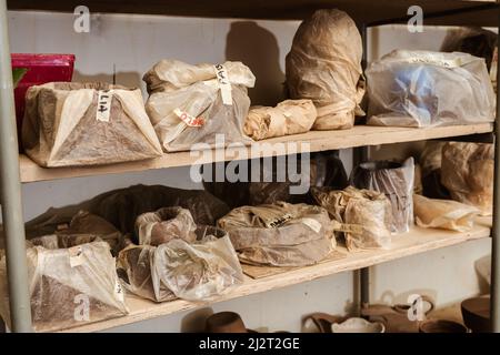 Étagères avec des paquets ou des sacs avec des morceaux d'argile faits à la main jusqu'à ce qu'ils soient tirés dans le four. Artisanat en argile et gres. Banque D'Images