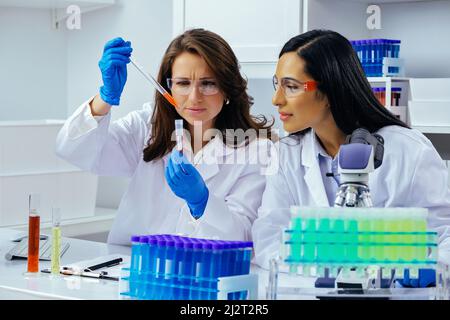 Deux belles jeunes femmes scientifiques travaillant en laboratoire avec des tubes à essai faisant de la recherche pharmaceutique Banque D'Images