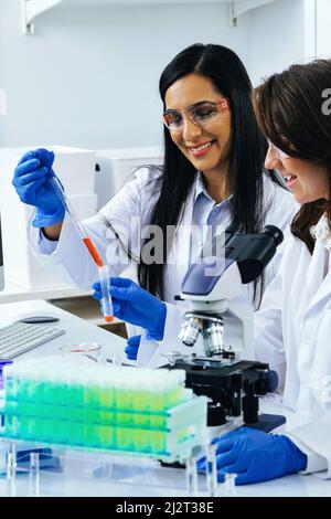 Deux belles jeunes scientifiques de sexe féminin travaillant en laboratoire avec des tubes à essai faisant de la recherche dans l'industrie pharmaceutique Banque D'Images