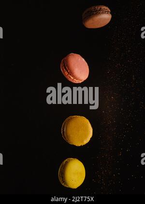 Sur fond noir avec des copeaux de chocolat macarons français dans un vol gelé. Minimalisme. Il n'y a aucune personne dans la photo. Il y a de l'espace libre pour moi Banque D'Images