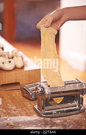 Pâtes la vista. Coupe courte d'une personne qui roule de la pâte fraîchement préparée dans un fabricant de pâtes. Banque D'Images