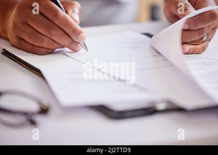 Remplir quelques documents. Photo courte d'un homme d'affaires méconnu qui remplit ses papiers pendant qu'il est assis dans son bureau. Banque D'Images