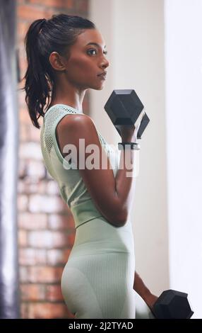 Ne soyez pas moyen, soyez sauvage. Photo d'une jeune femme qui s'est entraîner avec un haltère dans une salle de sport. Banque D'Images