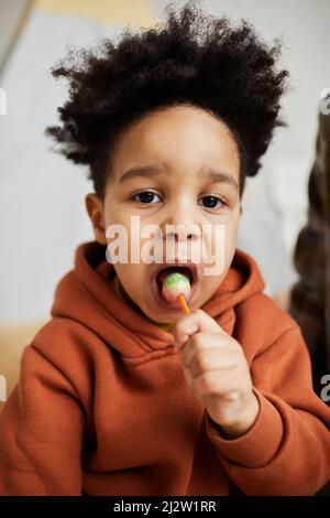 Portrait vertical en gros plan d'un petit garçon mignon tenant une boucle et regardant l'appareil photo dans la salle de jeu Banque D'Images