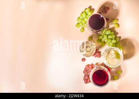 Verres de vin rouge et blanc avec soleil et ombres, avec bouteille et carafe, bouquet de raisins, sur fond crémeux, vue sur le dessus plat vin Banque D'Images