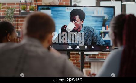 Gros plan de l'équipe multi-ethnique parlant sur la télécommunication d'appel vidéo à distance à l'homme exposé. Personnes utilisant la vidéoconférence en ligne au bureau. Discussion de conférence sur une connexion Internet. Banque D'Images