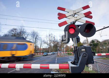 Pays-Bas, le train passe un passage à niveau à Arnhem avec des crossbucks, des feux rouges, des cloches électriques et des barrières à demi-barrière. Banque D'Images