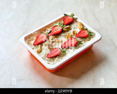 Traditionnel Ramadan turc dessert Gullac avec fraise. À emporter dans une boîte de rangement en plastique. Prêt à manger. Banque D'Images