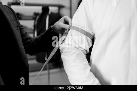 cet ancien modèle est conçu sur mesure pour prendre des mesures de poignet auprès du client dans un petit atelier d'atelier afin de créer un costume classique personnalisé Banque D'Images