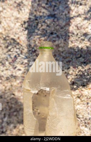 Directement au-dessus de la vue de la bouteille en plastique torée abandonnée sur le sable à la plage le jour ensoleillé Banque D'Images